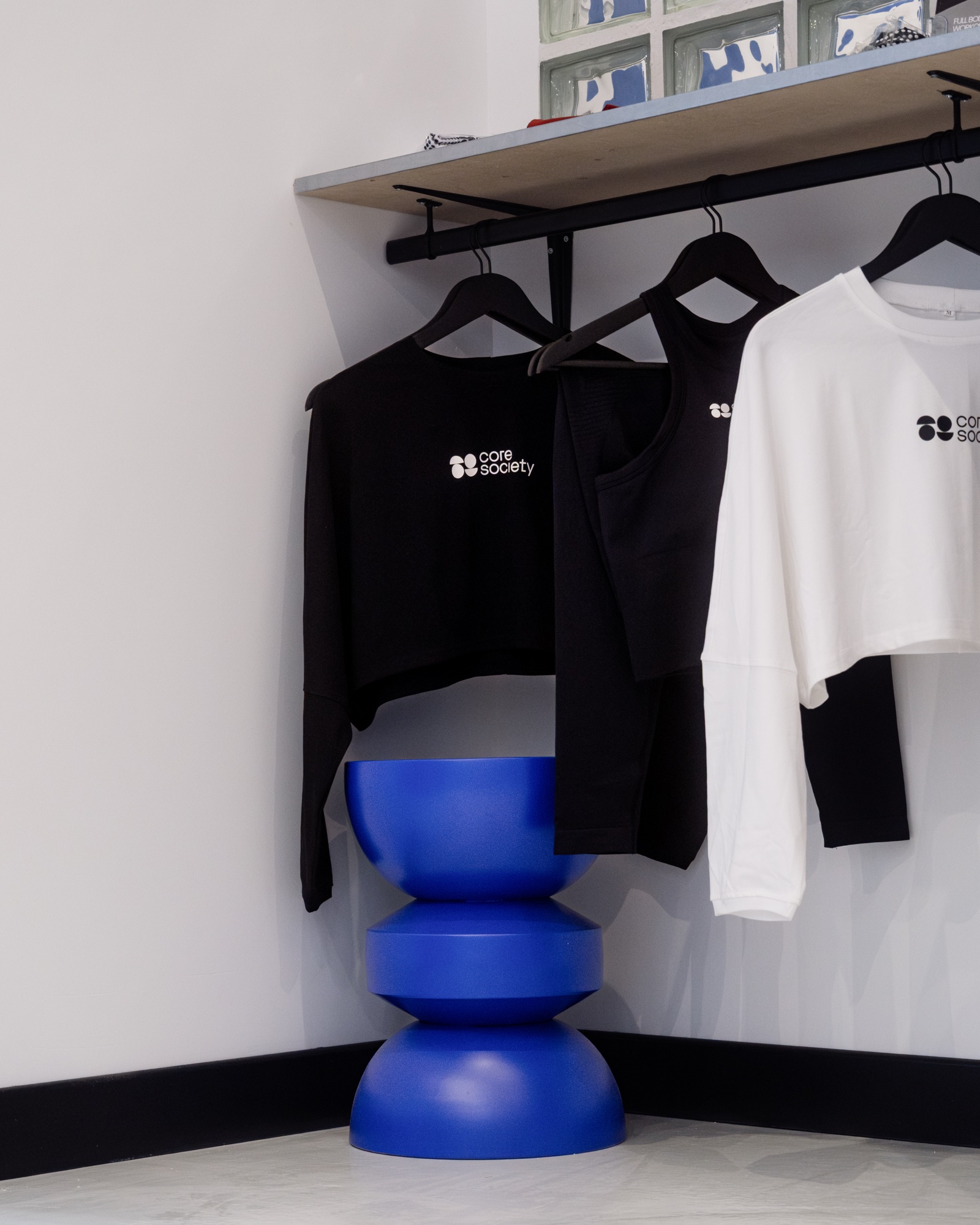 Vêtements Core Society et stool bleu signature dans le studio Bois-Colombes